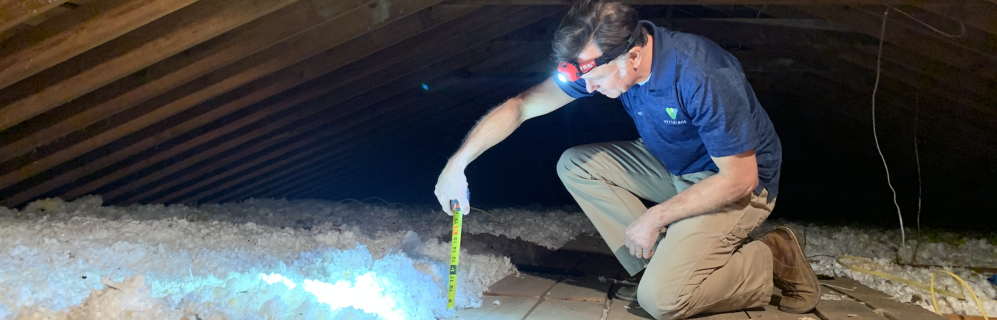 person in attic measuring materials